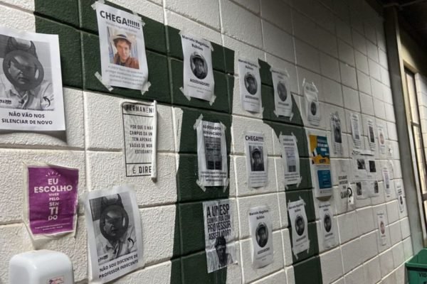 Imagem colorida mostra cartazes em uma parede; eles protestam contra um professor da Unesp acusado de assédio - Metrópoles