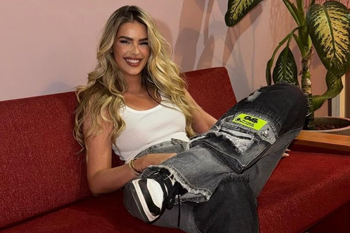 Yasmin Brunet posa, sorridente, sentada no sofá e com as pernas cruzadas - Metrópoles