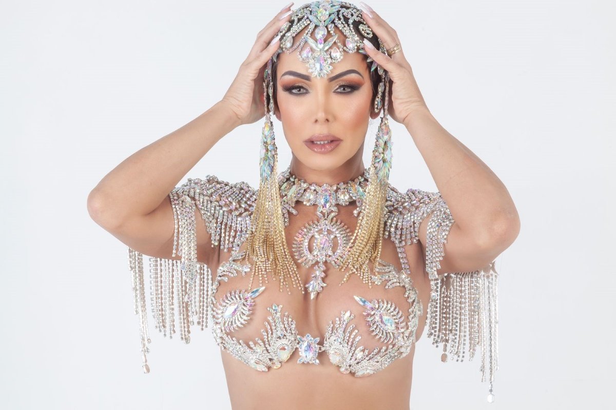 Imagem mostra rainha de bateria em frente a fundo branco - Metrópoles