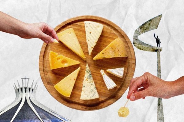 Na arte colorida, duas mãos degustam pedaços de queijo que estão dispostos em uma tábua - Metrópoles