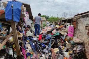 Homem em cima de lixo acumulado em quintal de casa - Metrópoles