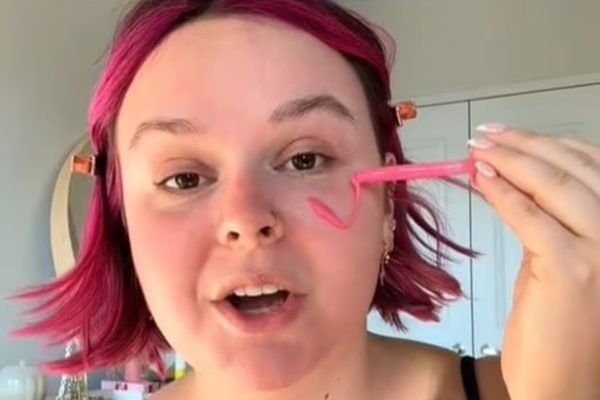 Mulher de cabelos cor-de-rosa aplicando maquiagem - Metrópoles