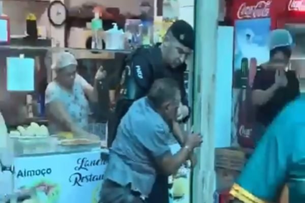 Policial prendendo homem suspeito de tenta matar ex-mulher a facadas em feira do Gama