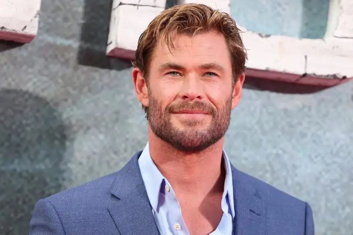 Foto colorida de Chris Hemsworth. Ele é um homem branco, de cabelo loiro, e usa terno azul - Metrópoles