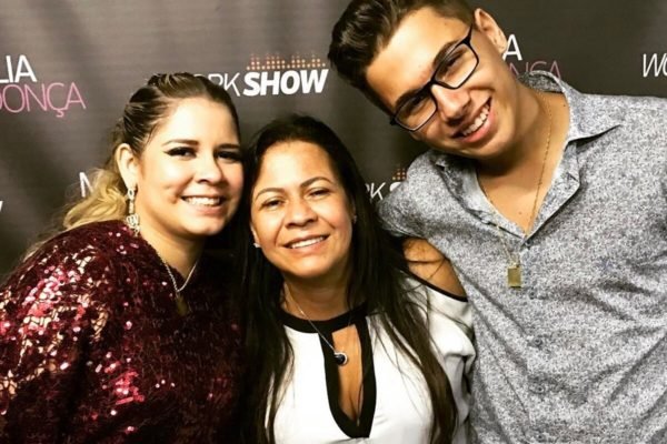 Marília Mendonça, a mãe e o irmão posam juntos e sorridentes durante um dos shows da cantora - Metrópoles