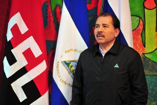 Imagem colorida mostra Daniel Ortega em frente as bandeiras da Frente Sandinista de Libertação Nacional (FSL) e da Nicarágua - Metrópoles