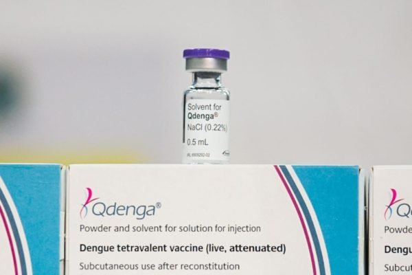 Vidro de vacina da dengue sobre caixa - Metrópoles