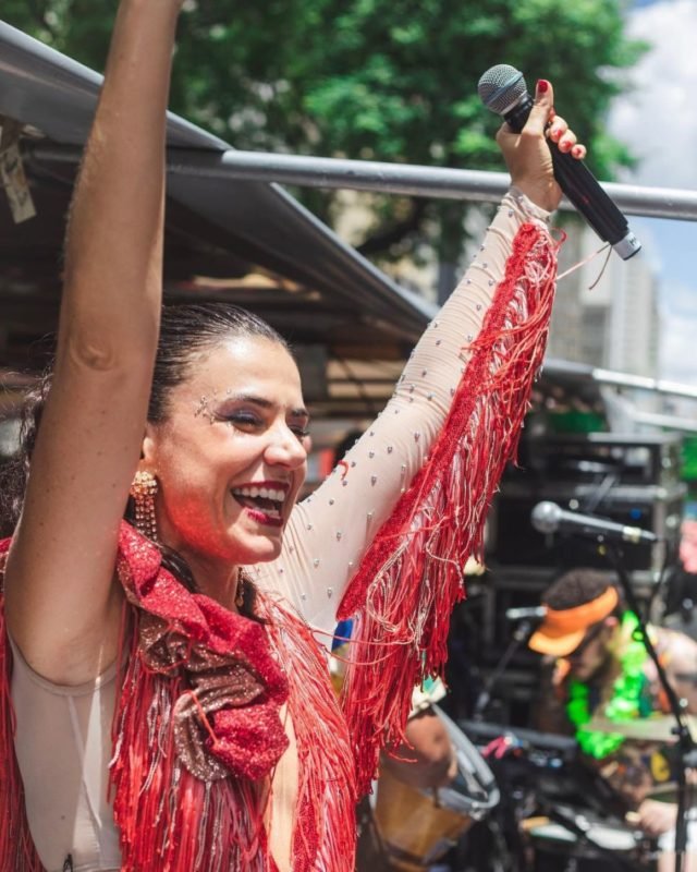 imagem colorida mostra cantora mariana aydar com braços erguidos. ela veste uma roupa vermelha. mariana é branca e tem cabelo castanho. metrópoles