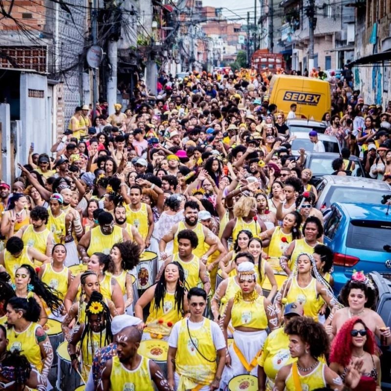 imagem colorida mostra multidão acompanhando bloco de carnaval em rua na periferia de são paulo - metrópoles