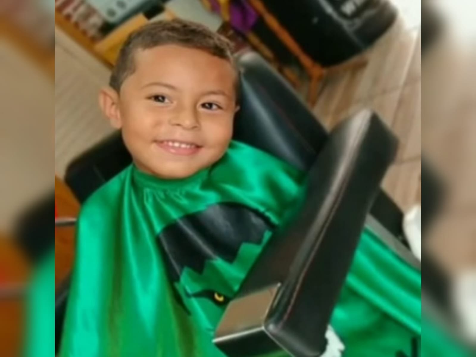 Imagem de menino sorrindo com capa de proteção verde - Metrópoles
