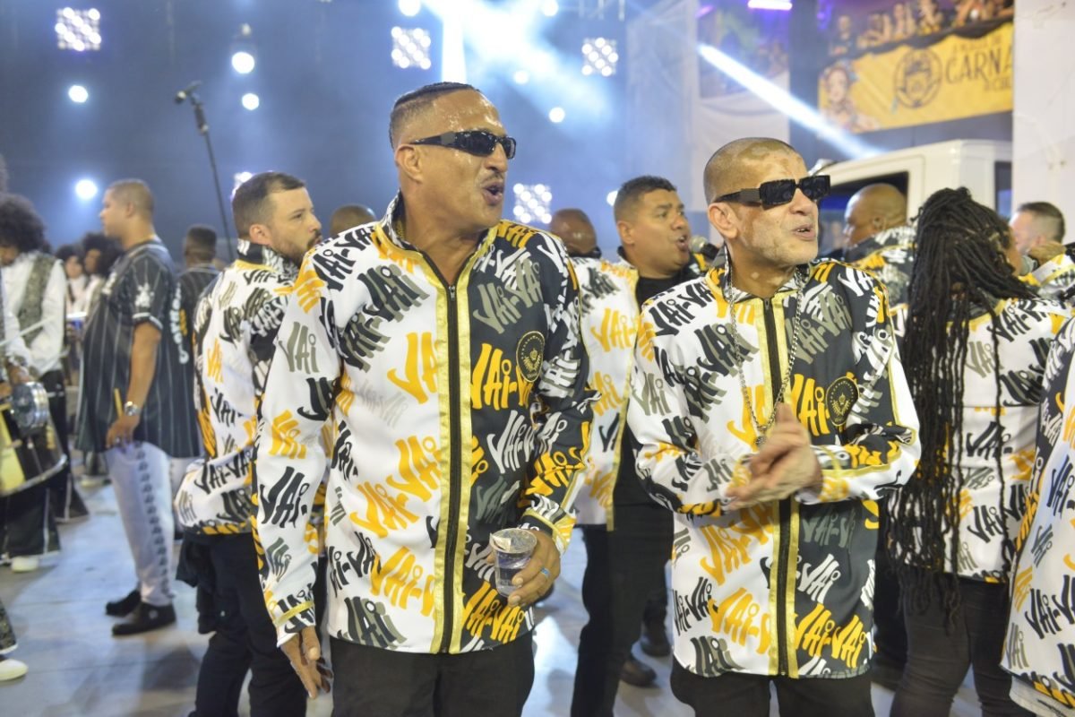 Imagem mostra dois homens em desfile de escola de samba - Metrópoles