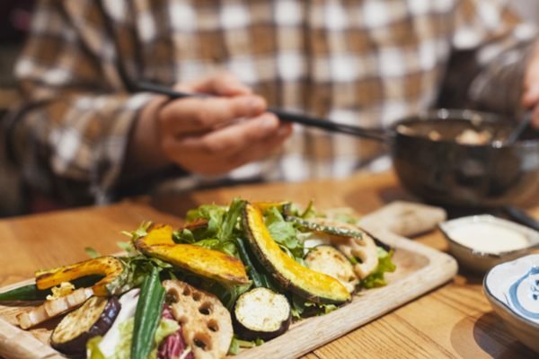 Homem serve refeição com vegetais - Metrópoles