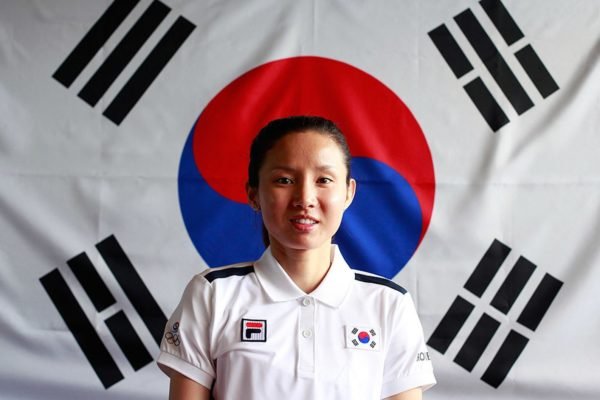 Foto colorida de Nam Hyun- Hee em frente à bandeira sul-coreana - Metrópoles