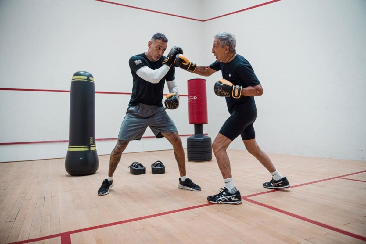 Fotografia colorida mostra Abilio Diniz lutando boxe com luvas e em ringue - Metrópoles