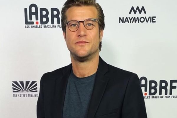 Diego Alemão posa de blazer preto, blusa cinza e óculos durante um evento - Metrópoles