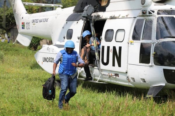 Imagem colorida mostra homem e mulher saindo de helicóptero da ONU - Metrópoles