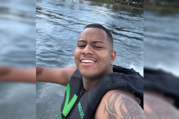 Foto de homem negro em um barco em meio a lago sorrindo
