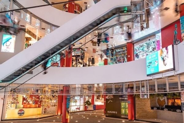 Imagem colorida mostra saguão de shopping com escada rolante - Metrópoles