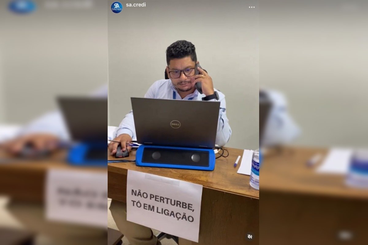 Foto colorida de homem no telefone com com computador