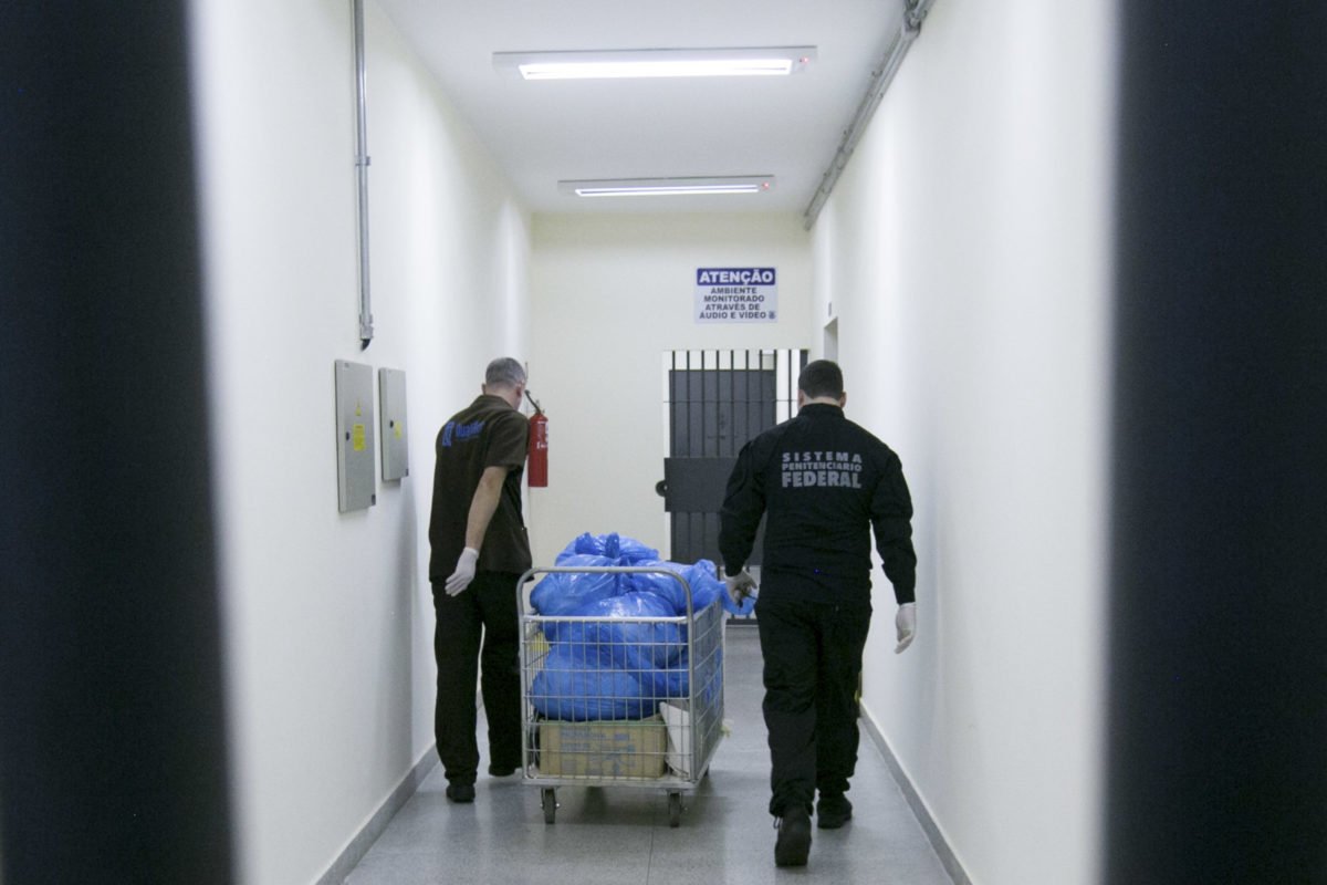 Agentes penitenciários carregam sacos de lixo em corredor do presídio federal - Metrópoles