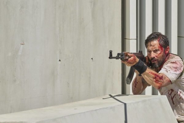 Foto colorida do filme Zona de Risco, com homem sangrando e segurando arma - Metrópoles