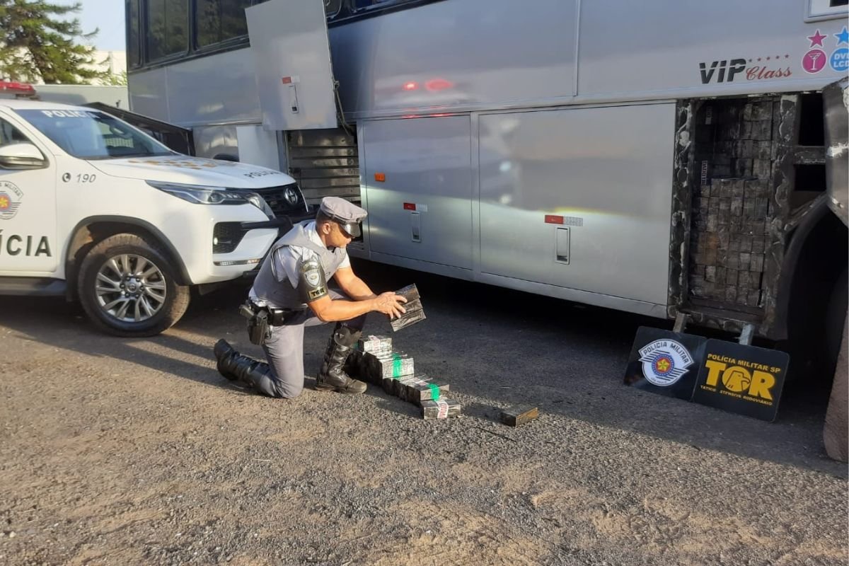 Imagem colorida mostra policial verificando carga de aparelhos celular que estava dentro de ônibus que ia para São Paulo - Metrópoles