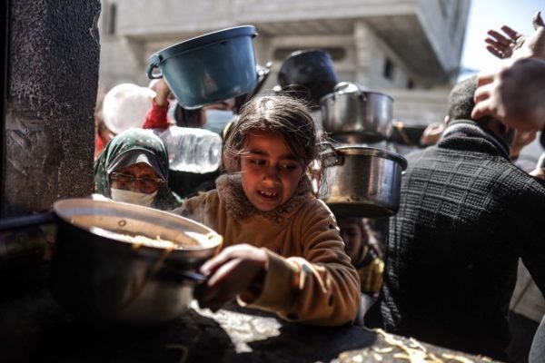 Foto colorida de criança na fila da comida na Faixa de Gaza - Metrópoles