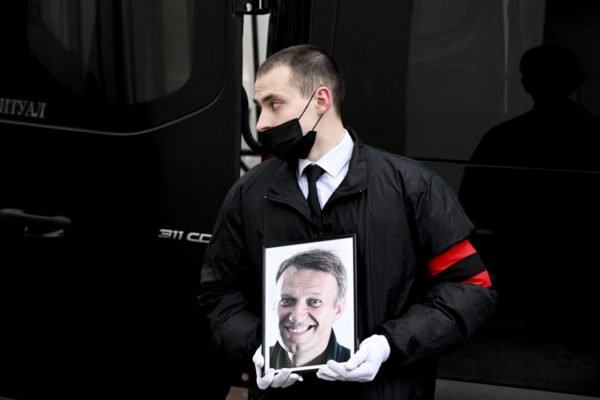 Homem segura foto de Alexei Navalny durante funeral em Moscou, Rússia - Metrópoles