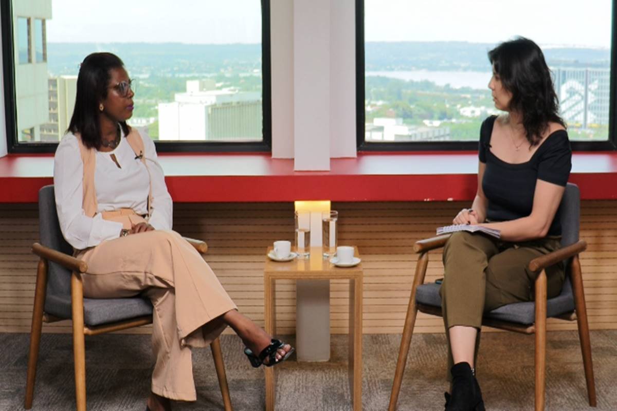 Foto colorida de entrevista, mulher negra ao lado de mulher branca