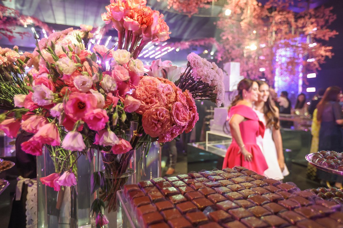 Mesa com doces e flores em meio a uma festa - Metrópoles