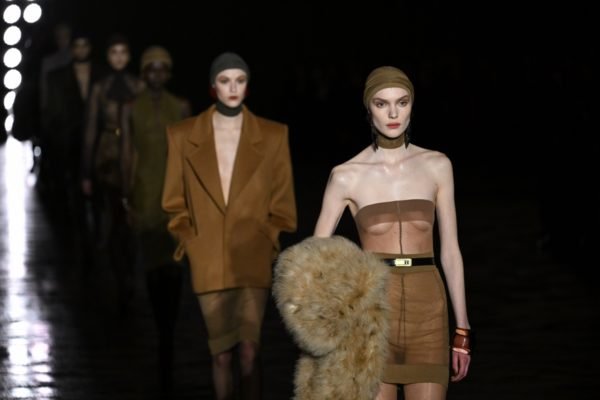 Na passarela da Saint Laurent, modelos desfilam com looks em tons terrosos. As duas usam toucas com meias - Metrópoles