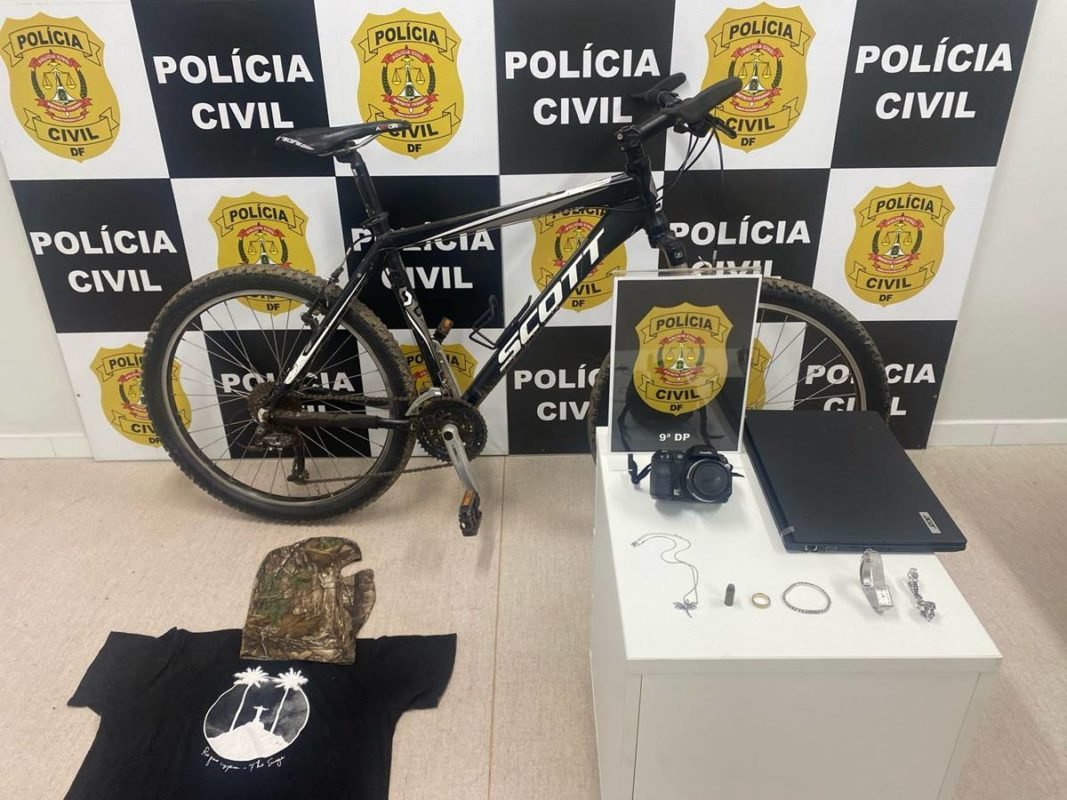 Bicicleta, camiseta e outros itens em frente a banner da polícia civil