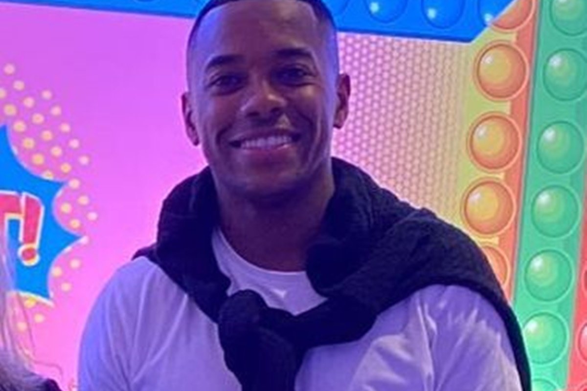 Robinho posa com uma blusa branca e um casaco nos ombros - Metrópoles