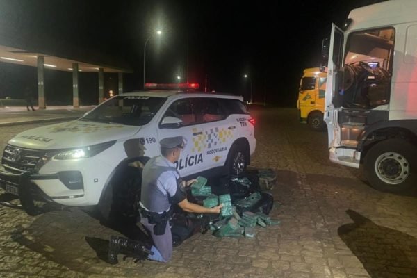 Imagem colorida mostra pacotes de drogas na frente de carro da polícia; motorista de caminhão que transportava os entorpecentes foi preso - Metrópoles