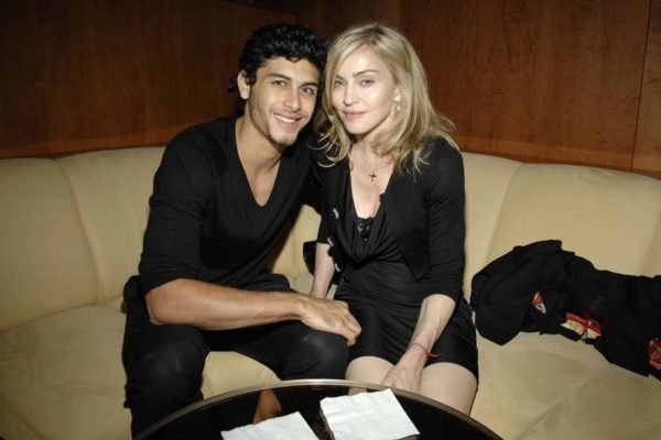 Foto colorida de Jesus Luz e Madonna sentados juntos de roupas pretas - Getty Images