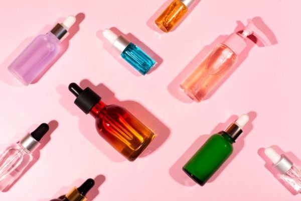 vidros coloridos de produtos de skincare em fundo rosa