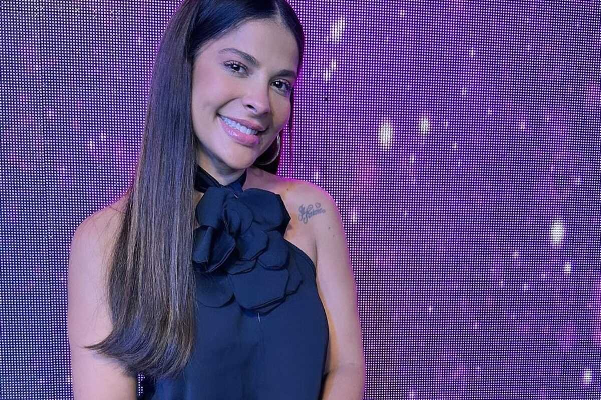 Gyselle Soares posa, sorridente, de vestido com uma flor no pescoço - Metrópoles