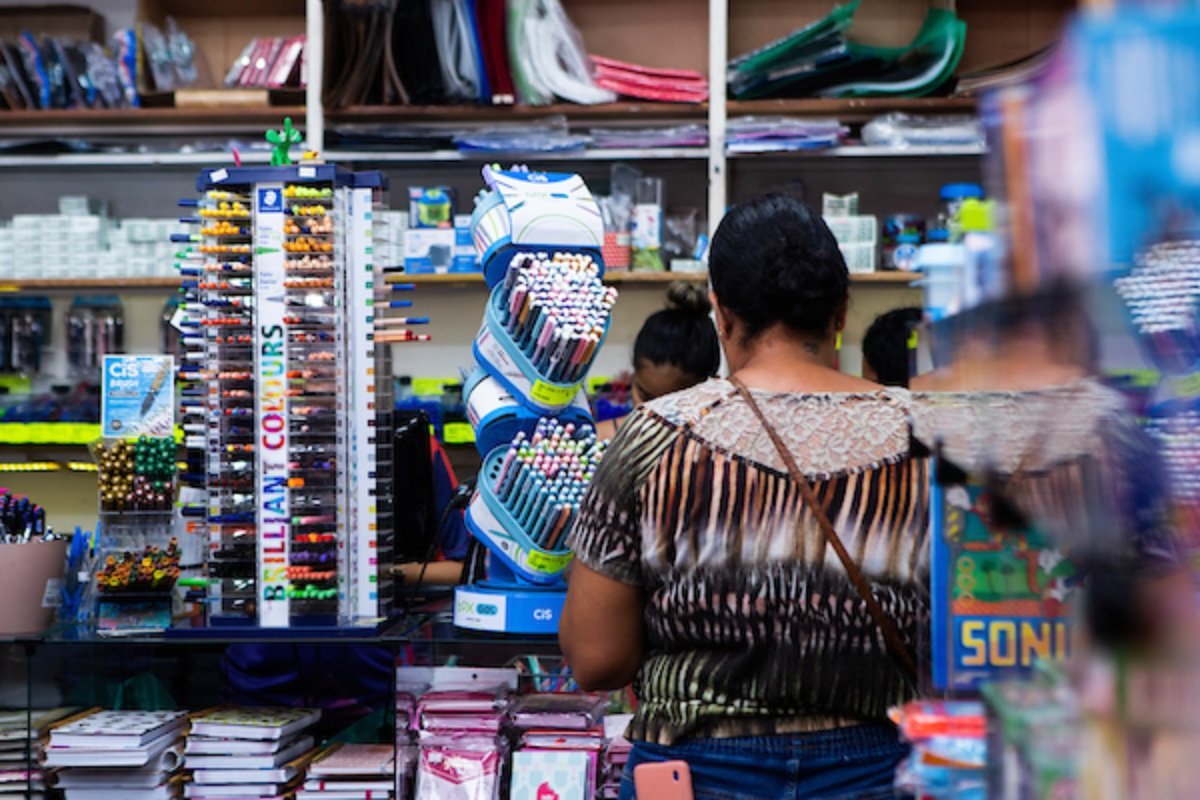 Fotografia colorida de uma mulher fazendo compras em uma papelaria