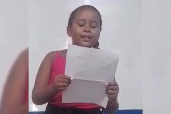 Imagem colorida da menina lendo a carta que escreveu aos colegas - Metrópoles