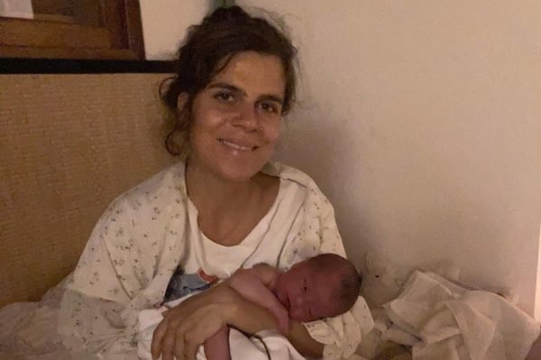 Mariana Maffeis e o filho, Varuna em foto colorida. Ela segura o bebê no colo e sorri - Metrópoles
