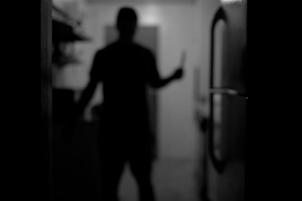Imagem preta em branca da silhueta de um homem segurando uma faca - Metrópoles
