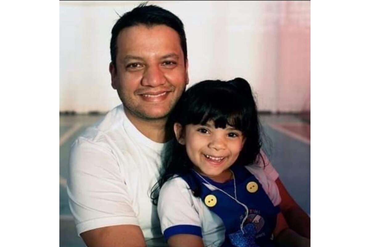 Foto colorida de homem sorrindo abraçando uma menina que também sorrri - Metrópoles