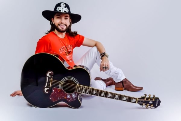 Dhonatan Coelho posa de chapéu e violão - Metrópoles