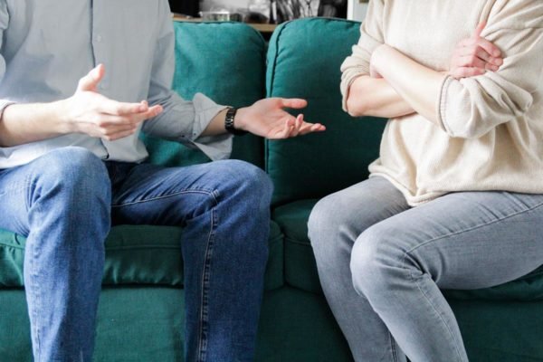 Foto colorida de um casal sentado no sofá - Metrópoles