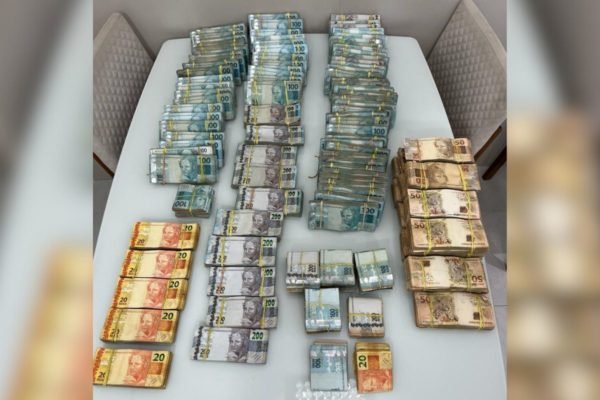Imagem colorida mostra notas de dinheiro encontradas na casa de empresário em cima de uma mesa - Metrópoles