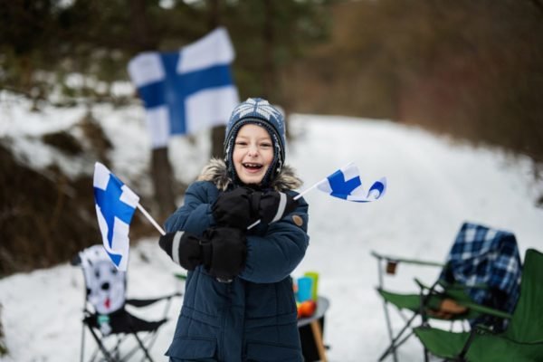 criança finlandesa segurando bandeiras da Finlândia