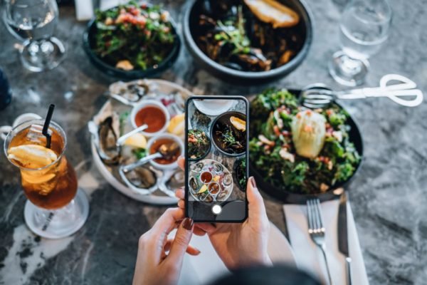 pessoa fotografando uma mesa de restaurante com comidas