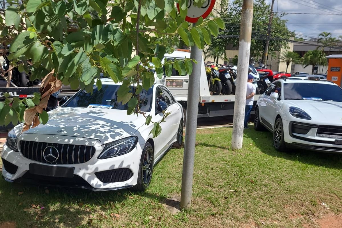 Imagem colorida mostra carros de luxo parados na rua - Metrópoles