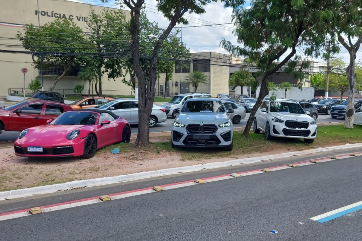 Imagem colorida mostra carros de luxo parados na rua - Metrópoles