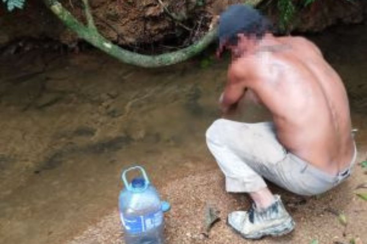 Imagem colorida mostra homem agachado colentado água de córrego - Metrópoles